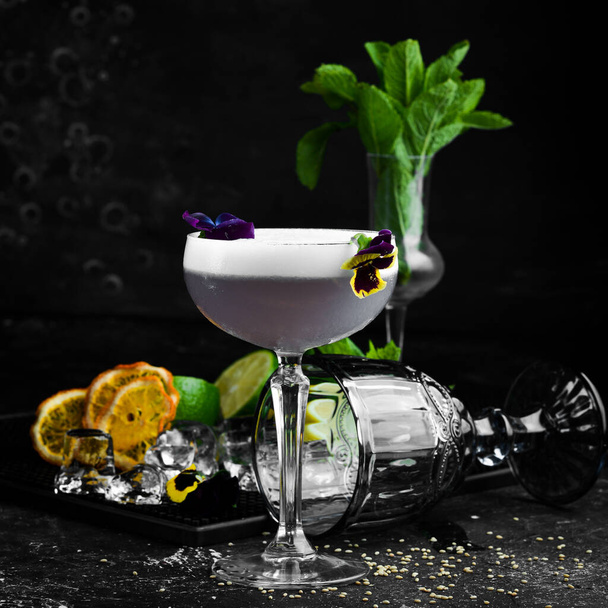 Alcoholic cocktail with fresh flowers in a glass. On a black background. Top view. - Valokuva, kuva