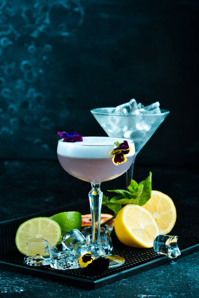 Alcoholic cocktail with fresh flowers in a glass. On a black background. Top view. - Foto, Imagen