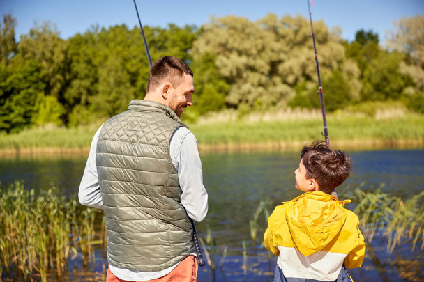happy smiling father and son fishing on river - Foto, Imagem