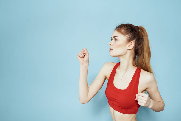 Sportieve vrouw rood tank top workout levensstijl gym blauw achtergrond - Foto, afbeelding