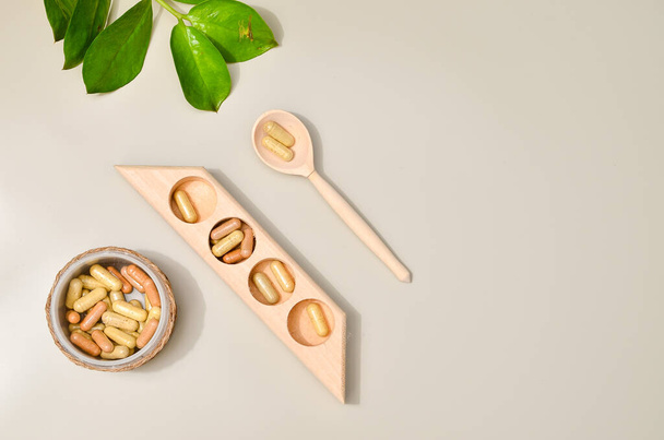 Herb in capsules in wooden bowl on pastel beige background. Beauty products for face and body skin care - Foto, imagen