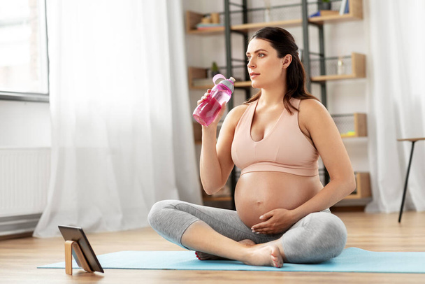 pregnant woman drinking water after yoga at home - Foto, imagen