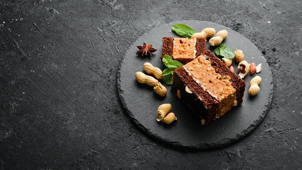 Peanut chocolate cake. Dessert. On a black background. Top view. - Photo, image