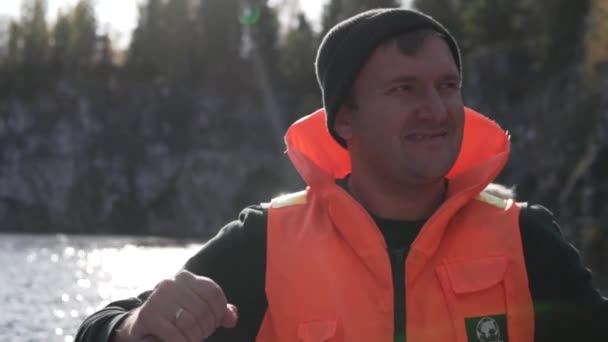 Muž v záchranné vestě pádluje na lodi - Záběry, video