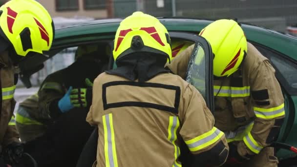 A tűzoltók az élet állkapcsait használják, hogy kiszabadítsák a csapdába esett áldozatot az autóból. - Felvétel, videó