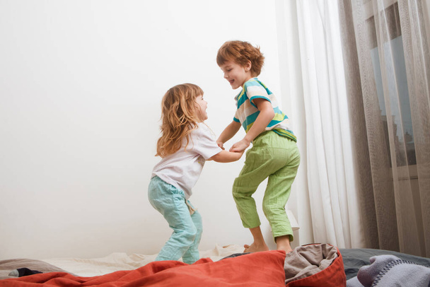 Niños hermanos hermano y hermana jugando y saltando en la cama. mañana familiar. - Foto, imagen