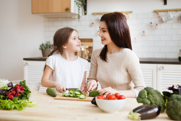 Mother and daughter in preparing healthy vegetables together in the kitchen. Help children to parents. - Fotoğraf, Görsel