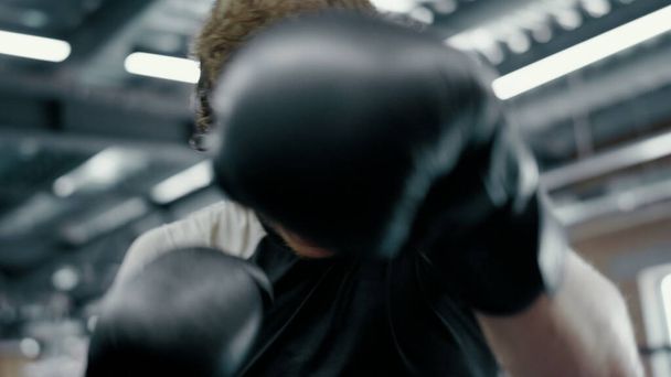Ένας ειλικρινής μαχητής ρίχνει χτυπήματα στο ρινγκ. Kickboxer στέκεται σε επιφυλακή στο γυμναστήριο - Φωτογραφία, εικόνα