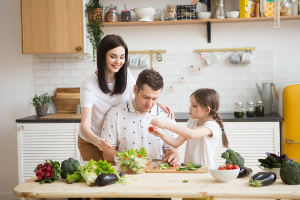 幸せな家庭の母。台所で一緒に健康な野菜を作るお父さんと娘。親に子供を助ける. - 写真・画像