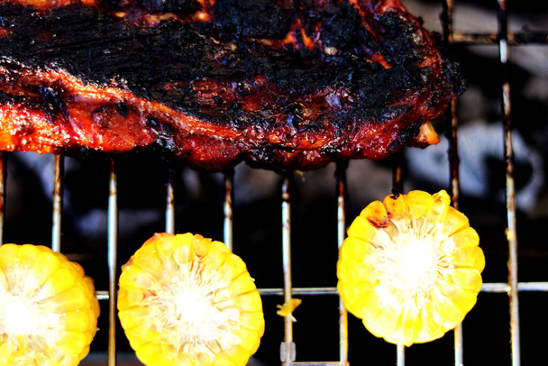 Grillen barbecue varkensribbetjes en maïs - direct boven, close-up - Foto, afbeelding