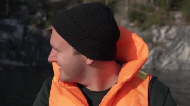 Een close-up van een man in een zwemvest op een boottocht over een prachtig meer  - Video