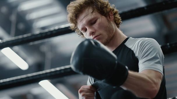 Peleador serio esperando pelea en el gimnasio. Kickboxer con guantes de boxeo - Foto, imagen