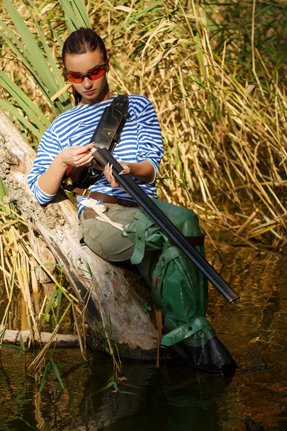 Girl reloads the gun on nature in a swamp. - Valokuva, kuva