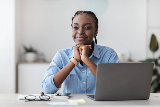 Красивая молодая чернокожая предпринимательница мечтает на рабочем месте в офисе - Фото, изображение