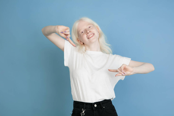 Portrait of beautiful caucasian albino girl isolated on blue studio background - Foto, afbeelding