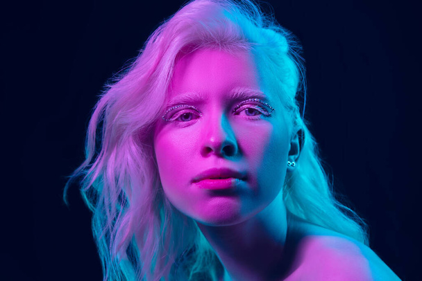 Portrait of beautiful albino girl isolated on dark studio background in neon light - Fotoğraf, Görsel