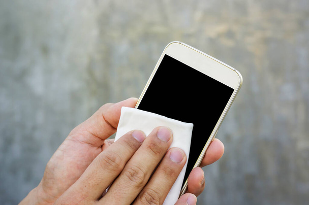 Człowiek czyszczący smartfona tkaniną z mikrofibry. - Zdjęcie, obraz