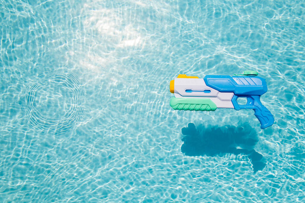 A child's blue water gun floats in the pool. A toy for playing in the pool or on the beach - Photo, Image