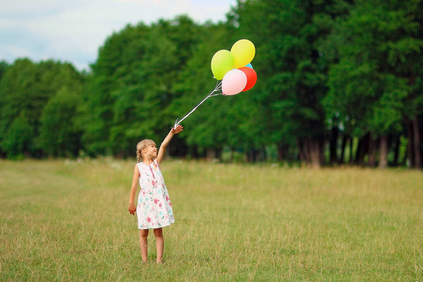 a happy little gilr  child with balloons  on nature - Фото, изображение