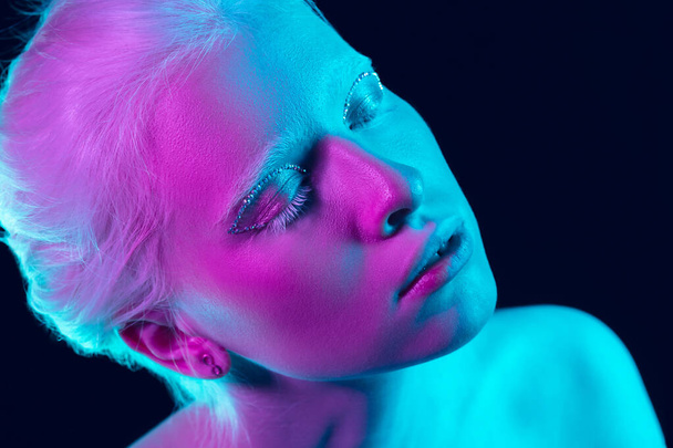 Portrait of beautiful albino girl isolated on dark studio background in neon light - Foto, Bild