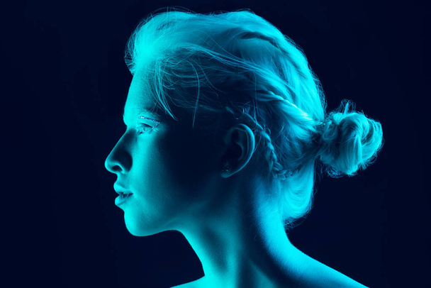 Portrait of beautiful albino girl isolated on dark studio background in neon light - Foto, Imagem