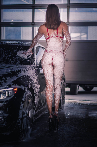 A lány fürdőruhában fekszik a motorháztetőn és mossa. - Fotó, kép