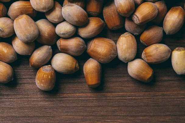 Pile of nuts. Whole nuts. Hazelnuts.Macro photo, close up, top view on wooden table. - Fotó, kép