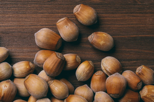 Pile of nuts. Whole nuts. Hazelnuts.Macro photo, close up, top view on wooden table. - Foto, Imagen