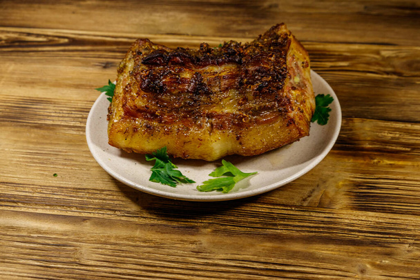 Pečené vepřové břicho v talíři na dřevěném stole - Fotografie, Obrázek