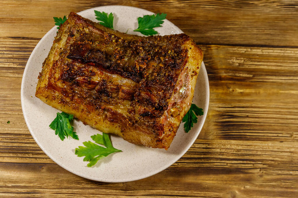 Ventre de porc cuit au four dans une assiette sur une table en bois. Vue du dessus - Photo, image