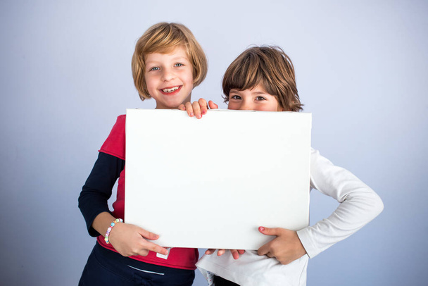 Two little girls hold empty white board. Copy space, space for writing - Foto, immagini