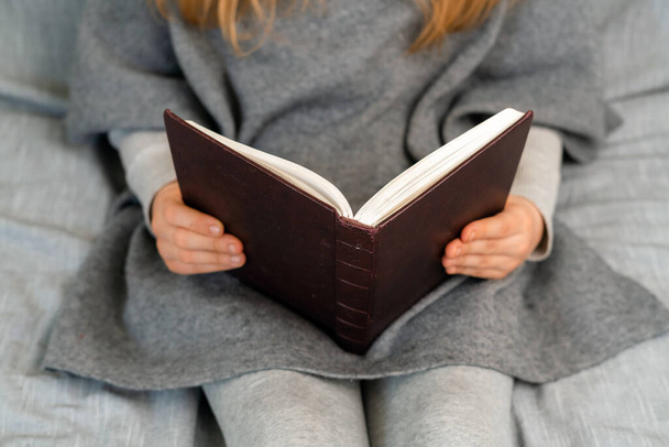 Fille blanche aux cheveux blonds lisant un livre. Jeune adolescent apprenant à l'école à domicile en quarantaine. - Photo, image