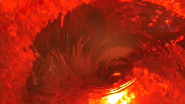 Symbool van de hel, inferno en oneindigheid. Rode vloeibare hypnotische aqua werveling draaien. Meditatieve robijn lichtgevende draaikolk. Mesmeriserende spiraalvormige tunnel van kristalvloeistof. Vurig surrealistisch ritmisch watergradiënt. - Foto, afbeelding