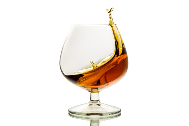 het glas met spatten brandy geïsoleerd - Foto, afbeelding