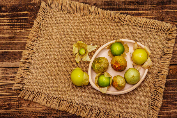 Scattered edible physalis with dry husk. Ripen cape gooseberries on old wooden table. Autumn harvest, healthy ingredient, top view - Fotoğraf, Görsel