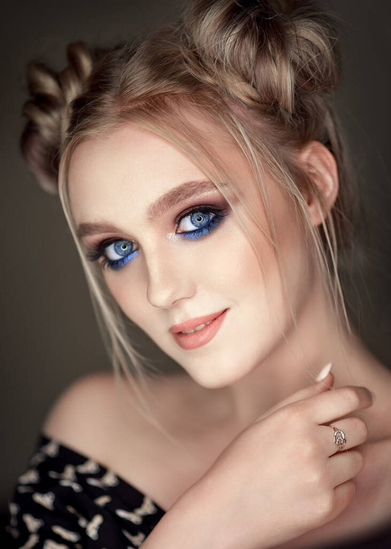 Close-up portrait of a girl with blue makeup with bunches on her head. - Foto, afbeelding