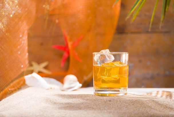 Whisky liqueur glass with ice cubes on the beach - Foto, Imagen