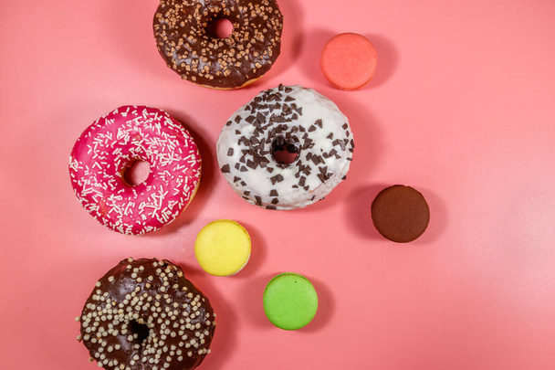 Leckere Donuts und Makronen auf rosa Hintergrund. Ansicht von oben - Foto, Bild