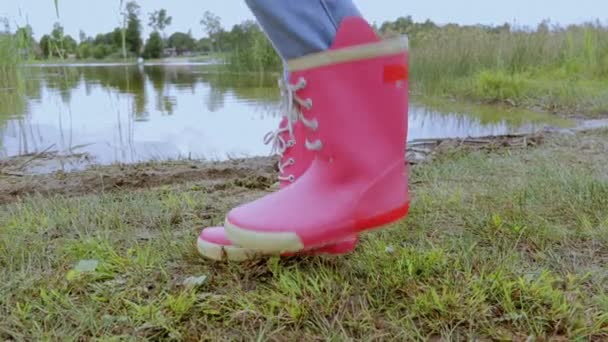 Przycięta dziewczynka w butach deszczowych w pobliżu jeziora - Materiał filmowy, wideo