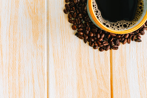 木製の背景にコーヒーとコーヒー豆のカップ、トップビュー、コピースペース - 写真・画像