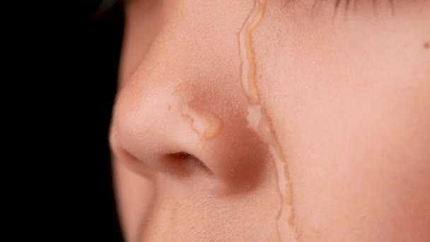 Water droplets flowing on the little girl's face. A little girl crying on a black background. Close up - Footage, Video