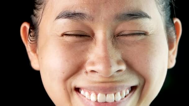 Detailní záběr portrét asijské ženy, která přestane být naštvaný a směje se na černém pozadí. - Záběry, video