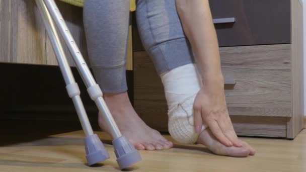 Mujer discapacitada lesionada con muletas sentada en la cama - Imágenes, Vídeo