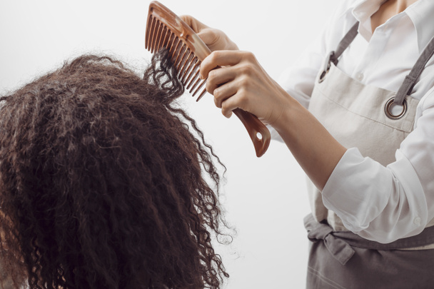 Μια Αφρο-Αμερικανίδα κόβει τα σγουρά μαλλιά της σε κουρείο.. - Φωτογραφία, εικόνα