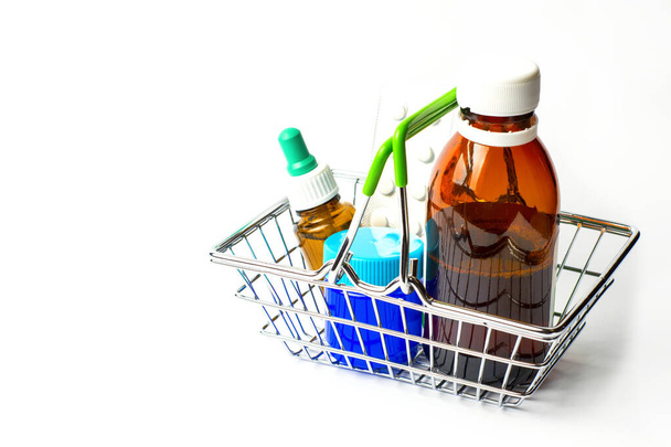 Lék proti nachlazení a chřipce v nákupním košíku na bílém pozadí.Tablety, nosní kapky, tření mast. - Fotografie, Obrázek