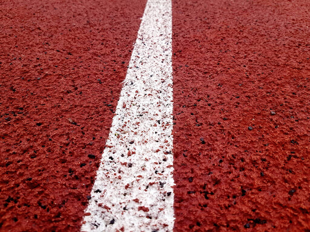 Carril blanco en una pista de atletismo del estadio rojo. De cerca curva pista de rodadura de goma.  - Foto, Imagen