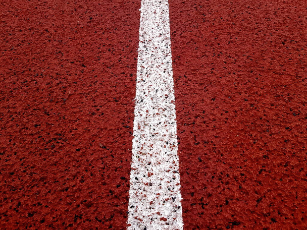 White lane on a red stadium running track. Close up curve running track rubber.  - Φωτογραφία, εικόνα