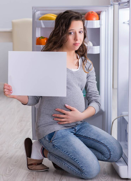 Femme enceinte près du réfrigérateur avec message vierge - Photo, image