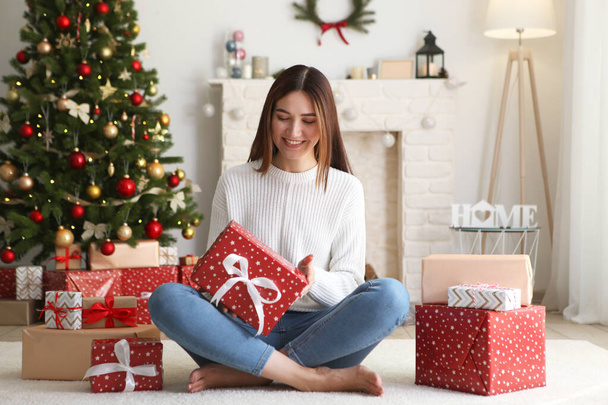 mooie jonge vrouw in een kerstinterieur met geschenken. Plaats voor tekst, feestelijke achtergrond - Foto, afbeelding