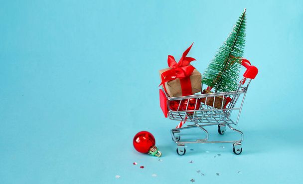 Kerstmis online winkelen concept. Winkelwagen met cadeaus, kerstdecor, kerstboom op een blauwe achtergrond. achtergrond. 3d illustratie. Kopieer ruimte, banner - Foto, afbeelding